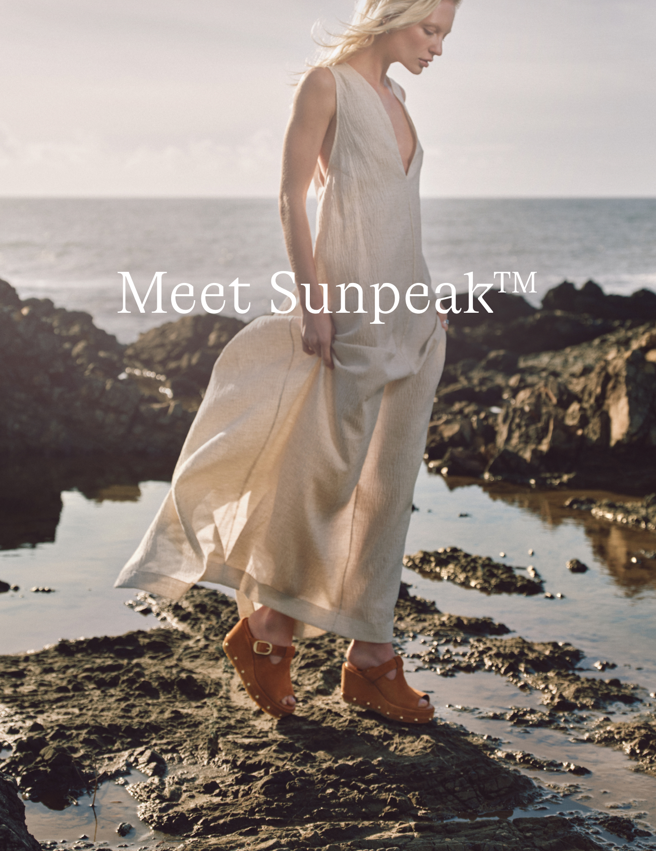 Woman wearing Sandals standing on rocky coast with waves behind