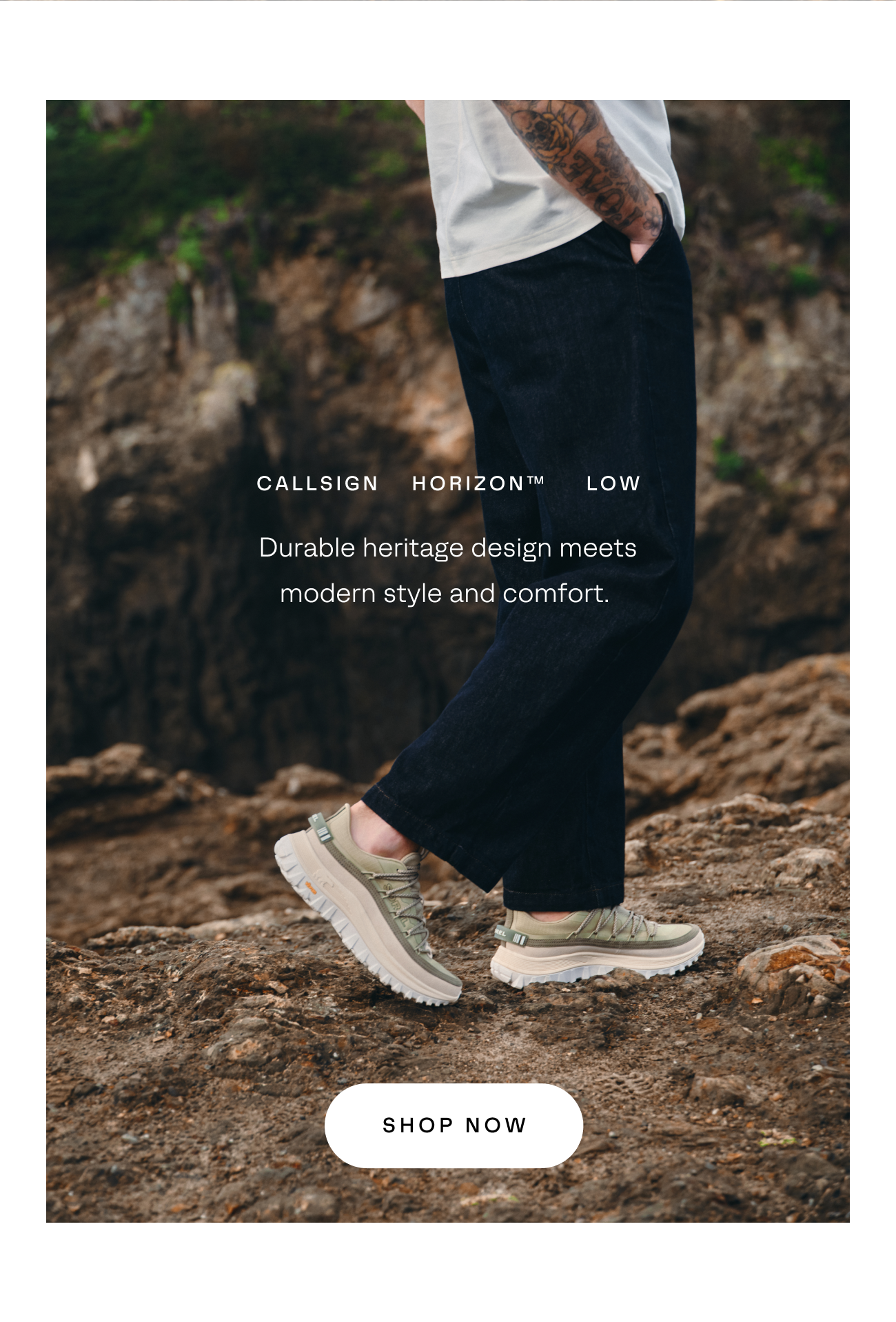 Man standing on dark rocky ground wearing dark pants and light colored Callsign Horizon Sneakers